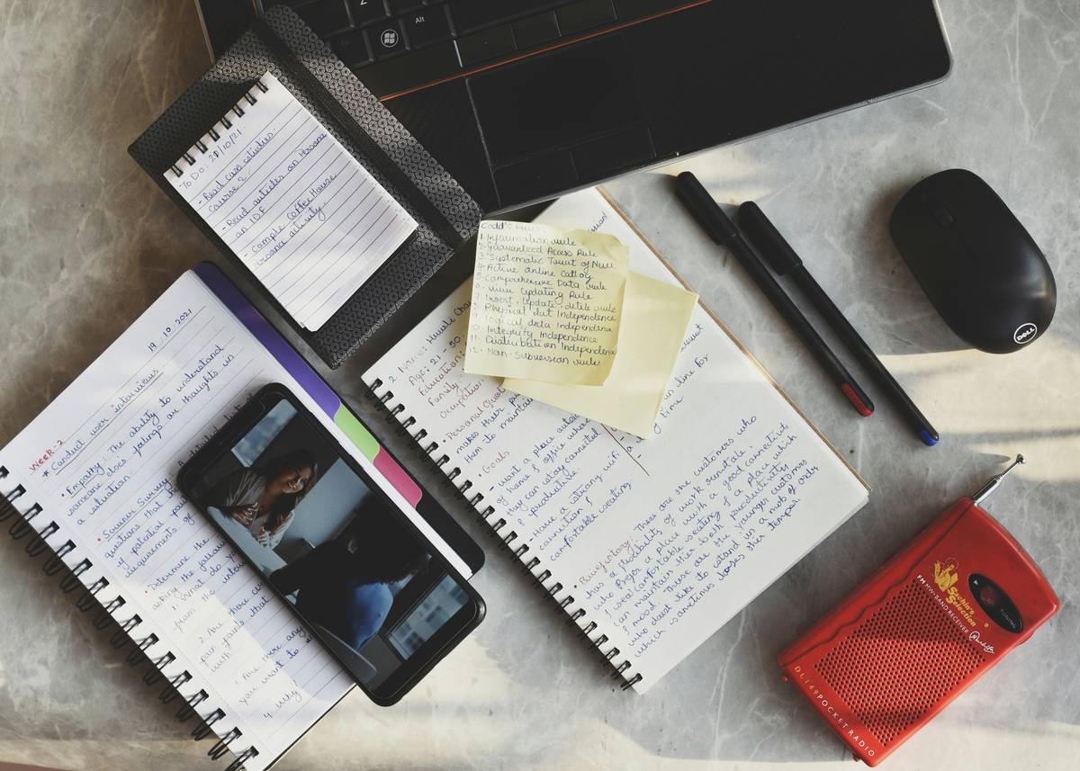 Woman using planning apps for goal tracking on tablet while journaling